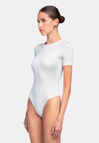 Korte mouwen witte body met een strakke pasvorm, gladde textuur en hoge beenopeningen. Bevat subtiele stikselaccenten.