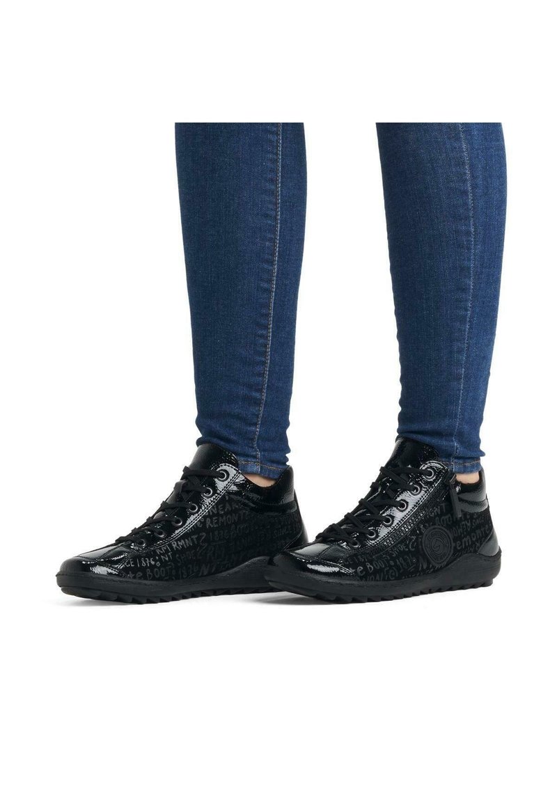 Black sneakers with a glossy finish, featuring embossed text patterns, round toe, lace-up design, and textured rubber sole.