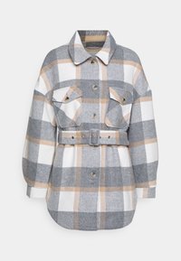 Camisa chaqueta de franela de gran tamaño en cuadros gris, blanco y marrón. Presenta dos bolsillos delanteros, botones y una cintura ajustable a juego.