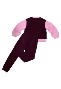 Completo a due pezzi composto da una felpa color marrone bordeaux con maniche rosa chiaro e pantaloni abbinati color marrone bordeaux. Tessuto morbido con polsini a costine.