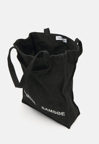 Black fabric tote bag with two long handles, featuring a spacious interior and white printed brand name "SAMSOE" on one side.