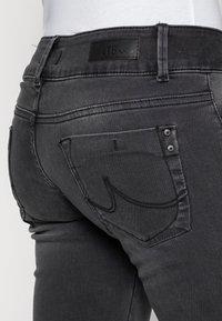Svarta denimjeans med hög midja, bakfickor med sömdetaljer och en logotagg bak. Texturerat tyg.