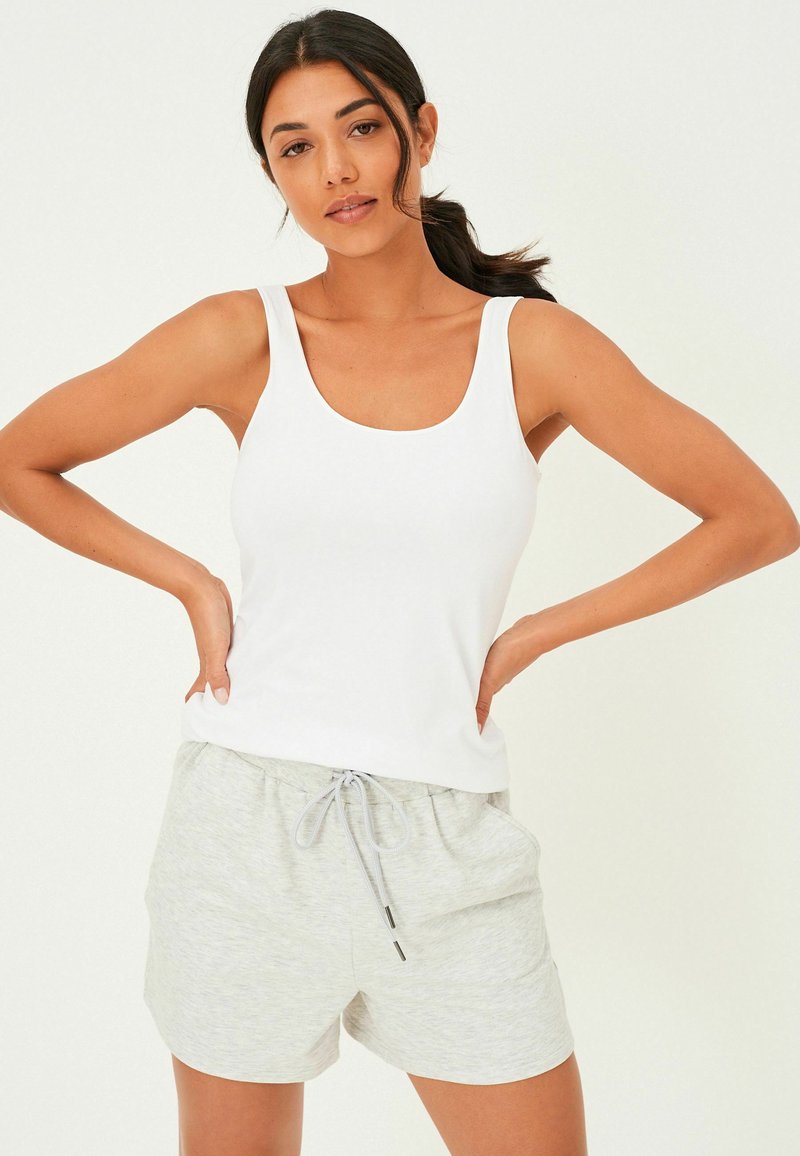 Hvid tætsiddende tanktop parret med lysegrå drawstring shorts, lavet af blødt materiale, med en afslappet pasform og sidelommer.