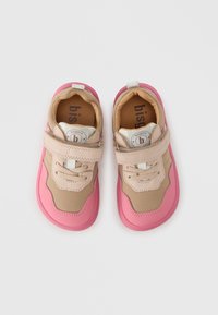 Ελαφριά αθλητικά παπούτσια με μπεζ επάνω μέρος, ροζ λαστιχένια σόλα,  λουράκι βέλκρο και διακοσμητικά σχέδια. Άνετος σχεδιασμός κατάλληλος για καθημερινή χρήση.