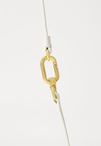 Bílý kožený pásek se zlatým kovovým zapínáním. Zapínání má oválný tvar s zesíleným hřebem, zajištěné malou kovovou páčkou.