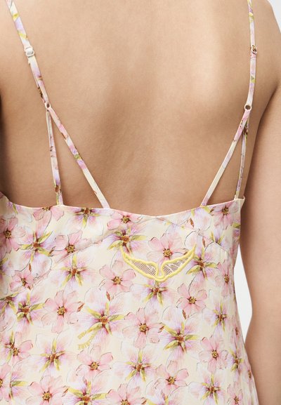 Οπίσθια όψη ατόμου που φορά ρούχο με ροζ ανοιχτή αποχρώσεις και λεπτές ρυθμιζόμενες τιράντες, με κίτρινη κεντημένη λεπτομέρεια κοντά στην πλάτη.