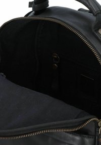 Zwarte lederen tas met een ritssluiting; het interieur heeft een donkere stofvoering, een ritsvak en contrasterende stikdetails.