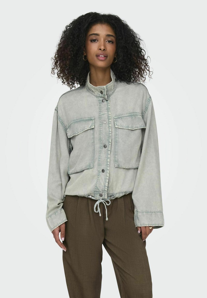 Vaate denim takki vaaleanvihreänä, jossa on nappikiinnitys, kaksi rintataskua, säädettävä nyörivyötärö ja pitkät hihat, joissa on elastiset hihansuut.