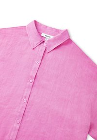 Camisa de lino rosa con cuello abotonado, con botones en la parte delantera y una tela texturizada. Etiqueta visible en el cuello.