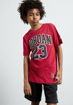 Rode katoenen t-shirt met "JORDAN 23" in zwarte letters, korte mouwen en een logo label op de zoom, gecombineerd met zwarte shorts.