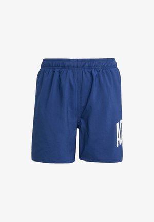 Marineblauwe zwembroek van lichtgewicht stof, met een elastische tailleband en een groot wit logo aan de linkerkant.