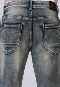 Verblasste blaue Jeans aus Denim mit geradem Bein, aufgesetzten Hintertaschen mit dezenten Gebrauchsspuren und einem schwarzen Taillenlabel.