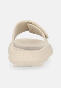 Sandal beige conschiena aperta, suola texturizzata e cinturino regolabile. Design leggero con un aspetto liscio e minimalista.