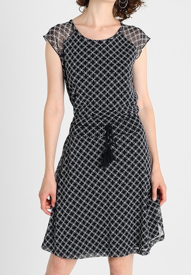 Vestido negro con mangas cortas y transparentes; presenta un patrón geométrico blanco. Cintura con cordón ajustable y detalle de borlas. Diseño acampanado.