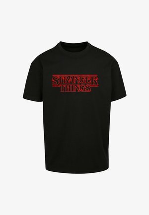 Svart T-skjorte med korte ermer og rød "Stranger Things"-tekstlogo plassert midt på forsiden.