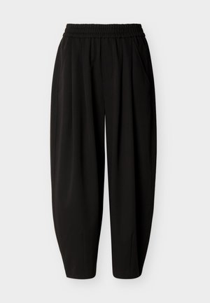 Pantalon noir ample avec ceinture élastique et poches latérales, fuselé aux chevilles.