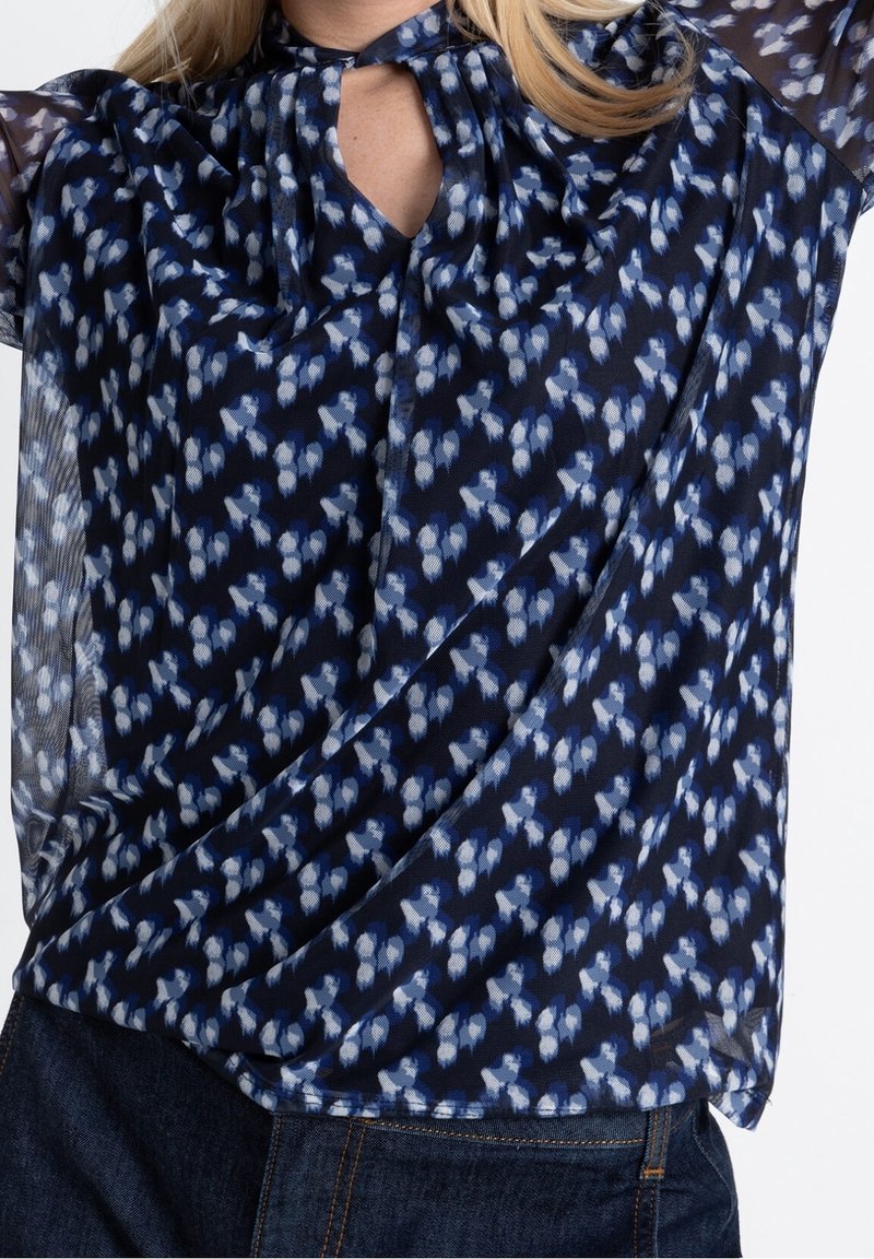 Marinebluse mit blauem und weißem Blumenmuster, Ausschnitt mit Schlüsselöffnung und durchsichtigen Ärmeln; leichtes Material mit fließendem Fall.