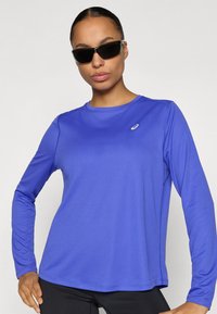 Αθλητική μπλούζα με μακριά μανίκια σε ζωηρό μπλε ύφασμα με υφή. Διαθέτει στρογγυλή λαιμόκοψη και διακριτικό λογότυπο στο στήθος.