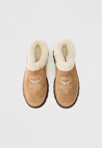 Botas de tornozelo em camurça castanho com um forro de pelúcia creme e costura decorativa na frente. Sola de borracha para aderência e durabilidade.