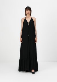 Mustapuku maxi-mekko, jossa on halterneck-hihnat, avonainen etuosa ja röyhelöhelma. Valmistettu kevyestä kankaasta, joka seuraa kauniisti vartalon muotoja.