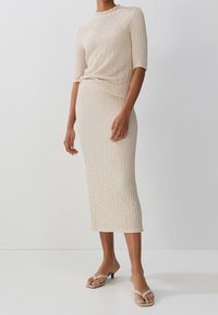 Beige texturerad stickad klänning med korta ärmar, knälång, slim fit. Matchad med ljusa klacksandaler. Slät, minimalistisk design.