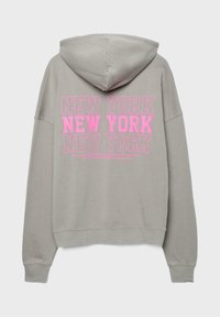 Lysegrå hættetrøje med "NEW YORK" trykt tre gange i store lyserøde bogstaver på ryggen.