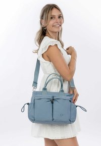 Helleblaue Stoffhandtasche mit zwei vorderen Reißverschlusstaschen, Oberhandgriffen und einem abnehmbaren Schultergurt. Glatte Textur, gepolstertes Design.