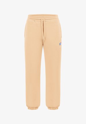 Beige Jogginghose mit elastischem Bund, Kordelzug, Seitentaschen, elastischen Bündchen und einem kleinen mehrfarbigen Logo am oberen Oberschenkel.
