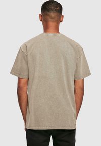 Kortærmet T-shirt med rund hals i en støvet beige farve med en falmet tekstur. Har et afslappet fit og stikninger langs sømmene.