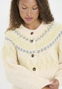 Cardigan tricotat în crem cu modele verzi și gri, închidere cu nasturi, guler și manșete cu un model răsucit, având un amestec de lână texturat și confortabil.