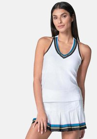 Top deportivo blanco sin mangas con un pronunciado escote en V, que presenta acentos a rayas en negro y colores. Combinado con una falda blanca con pliegues.