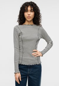 Dlhý rukáv s čiernymi a bielymi prúžkami, volánovým lemom a manžetami, úzky strih a okrúhly výstrih.