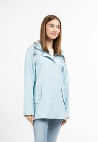 Jachetă impermeabilă de culoare albastru deschis, cu glugă gri, capse și două buzunare laterale. Are un design casual și mâneci drept.