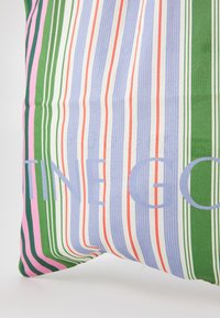 Cuscino a righe multicolori con tonalità di verde, rosa, blu e rosso, realizzato in tessuto texturizzato e con la scritta grande: "VALENTINE GO" in blu chiaro.