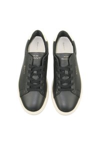 Black leather sneakers with white accents, round toe, and black laces. GANT logo in gold on the side and tongue. Smooth texture.