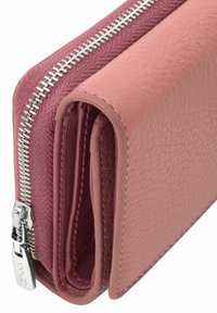 Złożony różowy skórzany portfel z srebrnym zamkiem błyskawicznym i widocznym przeszyciem na białym tle.