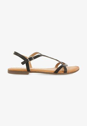 Sandalias negras de tiras con suela plana, que cuentan con un cierre de hebilla y una plantilla marrón, diseñadas para la comodidad y el estilo.