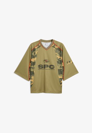 Locker sitzendes olivgrünes Sportshirt mit Camouflage-Paneelen, roter Paspelierung, V-Ausschnitt und "SPC SPORTSTYLE PUMA COLLECTIVE"-Logo auf der Vorderseite.