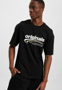 Svart bomull T-skjorte med et iøynefallende "originals" grafikk i hvitt, avslappet passform, korte ermer, med glatt tekstur og rund halsdesign.