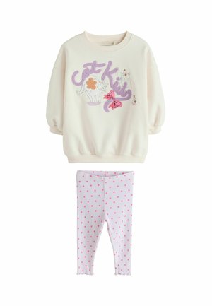 Crèmesweatshirt met kattenillustraties en paarse accenten, gecombineerd met roze legging met witte stippen. Zachte stof, geribbelde manchetten en een gerimpelde zoom.