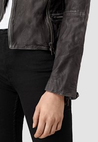 Giacca da motociclista in pelle nera con finitura testurizzata, tasche con zip e design accorciato. Abbinala a pantaloni neri.