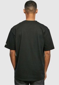 Sort T-shirt med korte ærmer, rund hals og en afslappet pasform. Har broderet detalje på venstre ærme.
