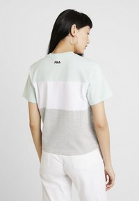T-shirt à manches courtes en color-block de FILA. Comprend des sections bleu clair, blanc et gris avec un col rond et un logo dans le dos.