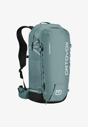 Tropfenfarbener Rucksack mit aufsteigender Form und strukturiertem Finish, verstellbaren Trägern, externen Befestigungsschlaufen und einer Seitentasche. Verfügt über auffällige weiße Markenbeschriftung.