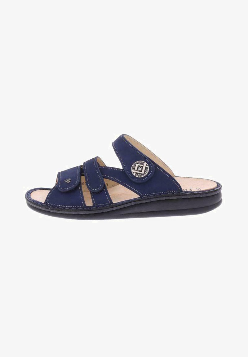 Navy blue slide sandals made of leather, featuring two Velcro straps, a rounded toe, and a textured black rubber sole with stitching details.