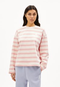 Sweatshirt à manches longues rayé rose et blanc avec une coupe décontractée et un petit logo blanc sur la poitrine ; associé à un pantalon de survêtement violet clair.