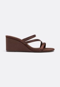 Brun kile-sandal med tre tynde remme over foden og åben tå på en ensfarvet hvid baggrund.