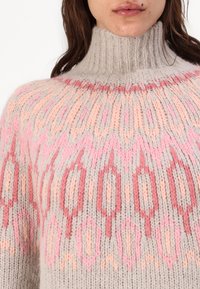 Gaisas pelēkas adītas turtlenecks džemperis ar pasteļrozā un koralliem ziedu rakstiem, ribota apkakle un teksturēta auduma virsma.