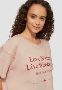 Lichtroze katoenen T-shirt met een ontspannen pasvorm, ronde halslijn en rode tekstprint met de tekst "Love Natur Live Weeker, Own Your World."