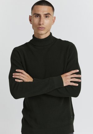 Suéter de cuello alto de color verde oscuro con canalé y mangas largas. Presenta un ajuste relajado y una textura sutil. Sin logotipos ni patrones visibles.